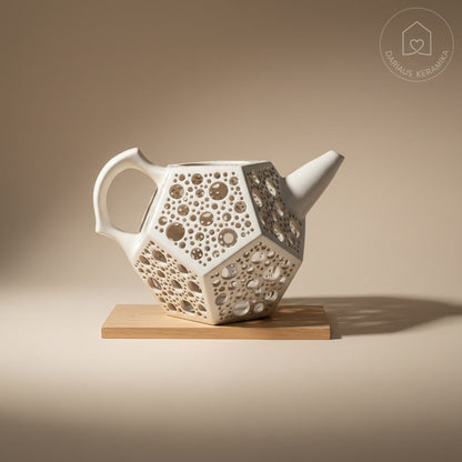 Ažūrinė balta keraminė žvakidė arbatinukas dodekaedro formos skleidžianti šviesą tamsoje ant medinio stalo