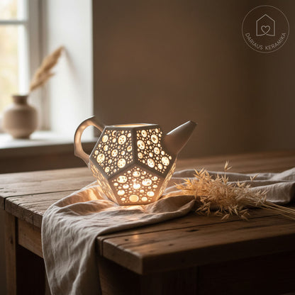 Ažūrinė balta keraminė žvakidė arbatinukas dodekaedro formos skleidžianti šviesą tamsoje ant medinio stalo