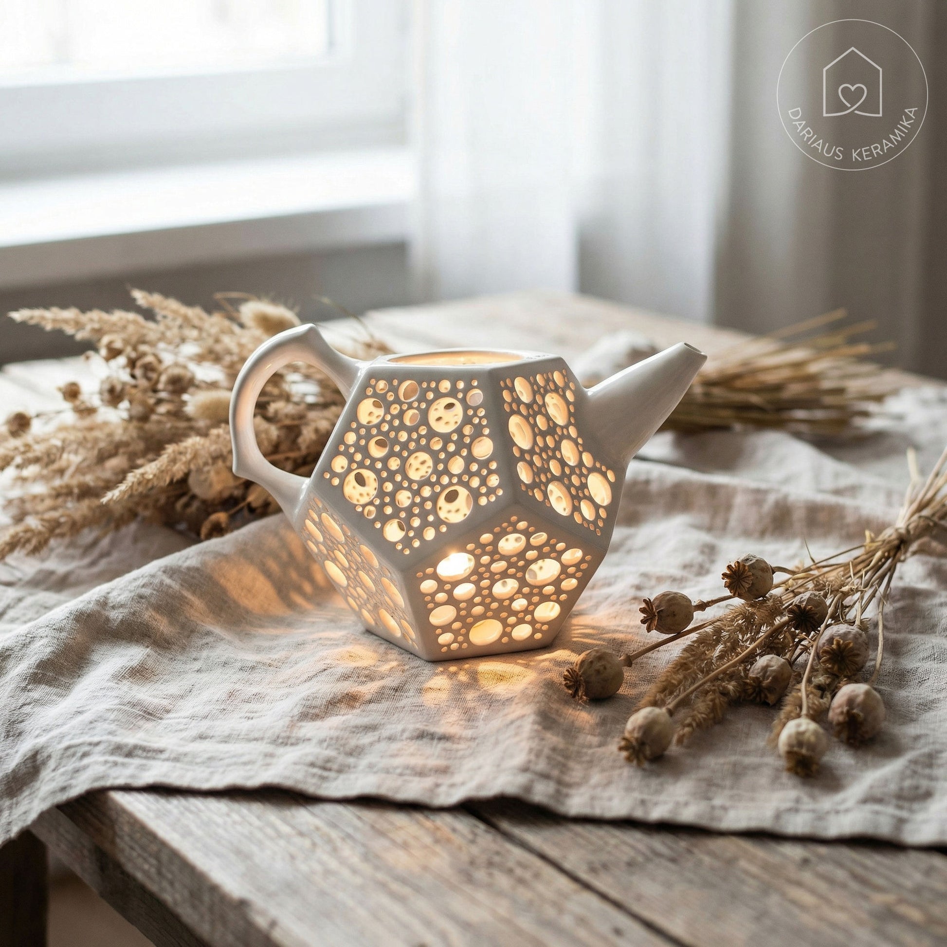 Ažūrinė balta keraminė žvakidė arbatinukas dodekaedro formos skleidžianti šviesą tamsoje ant medinio stalo